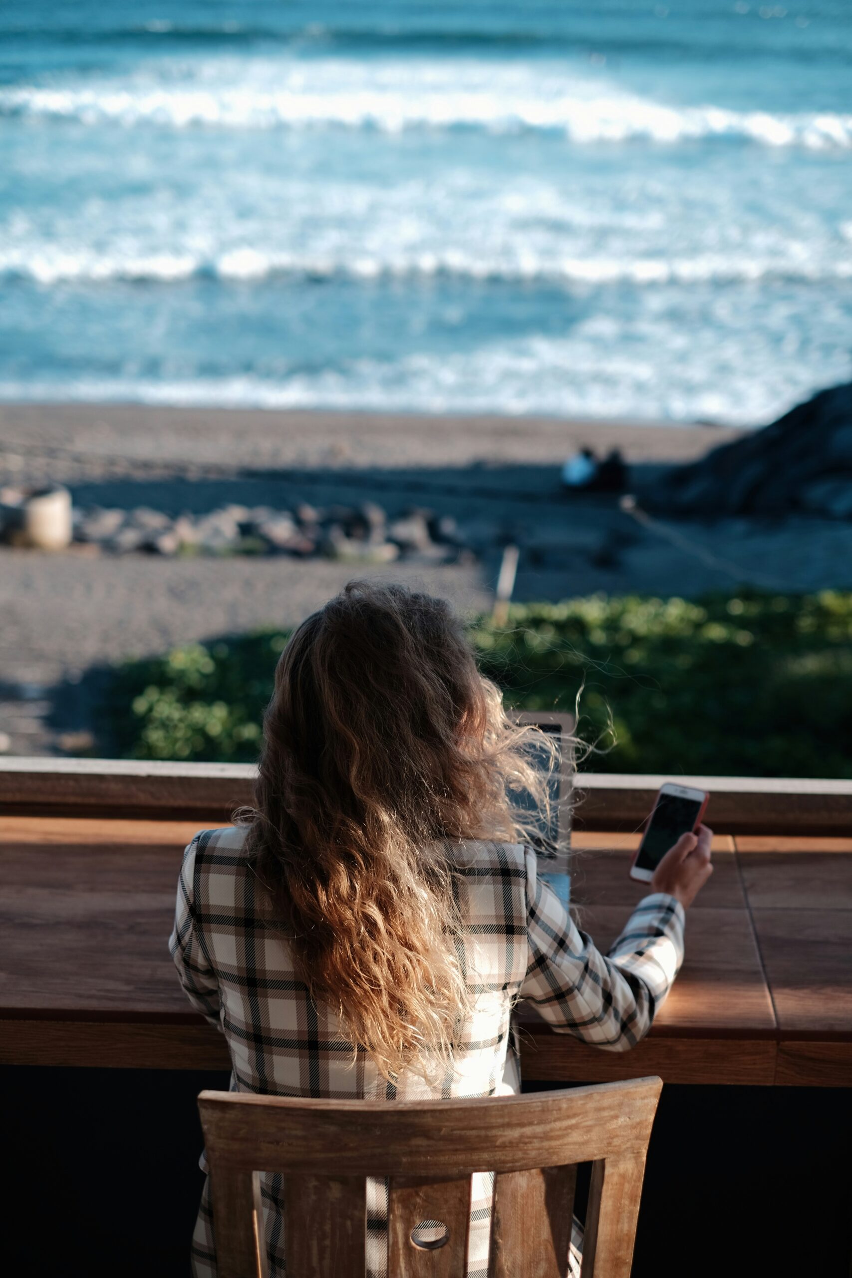 Person checking mail on phone by the beach